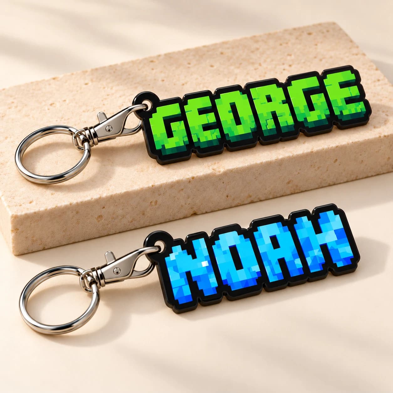 Digital product mockup of GEORGE and NOAH pixel name keyrings on black acrylic.