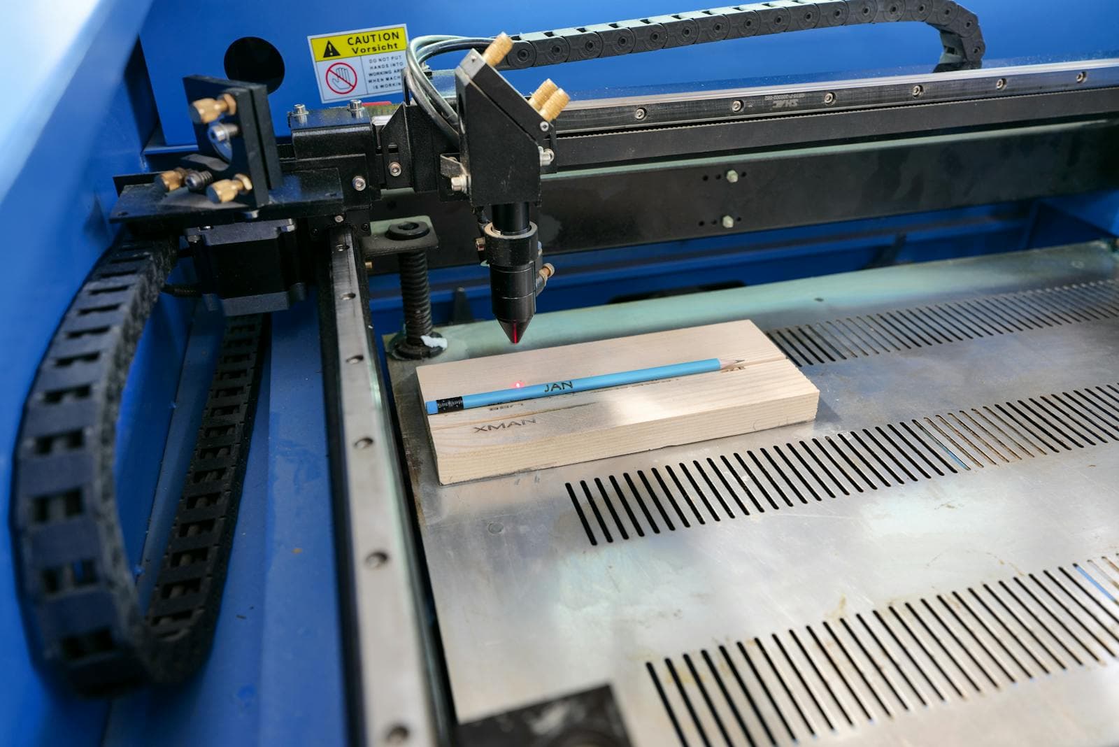 A laser engraver marking a wooden workpiece